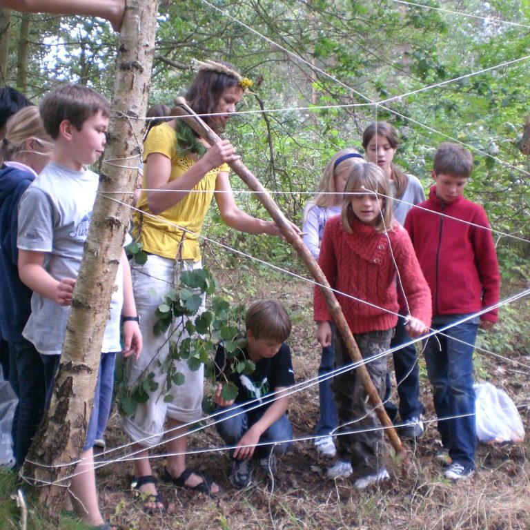 Eine Gruppe von Kindern und Erwachsenen beim Erforschen des Waldes.