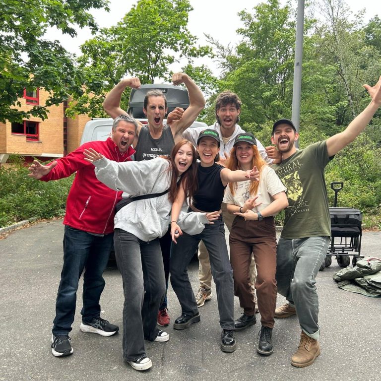 Eine Gruppe von sieben Personen posiert fröhlich im Freien.