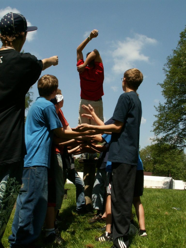 Kinder stehen in einem Kreis und fangen einen Jungen, der in die Luft springt.