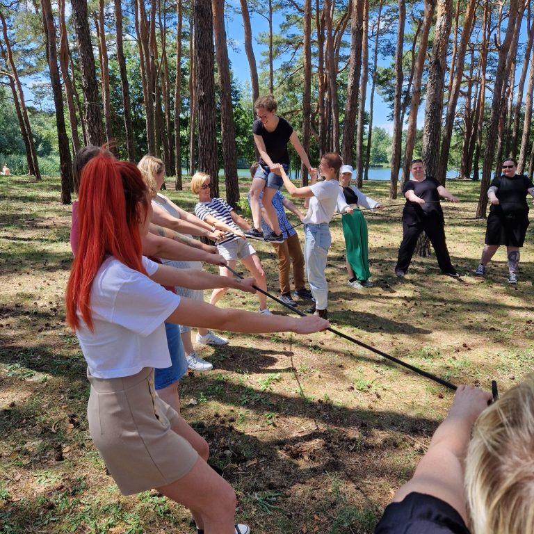 Gruppe von Menschen zieht an einem Seil in einem Waldgebiet.