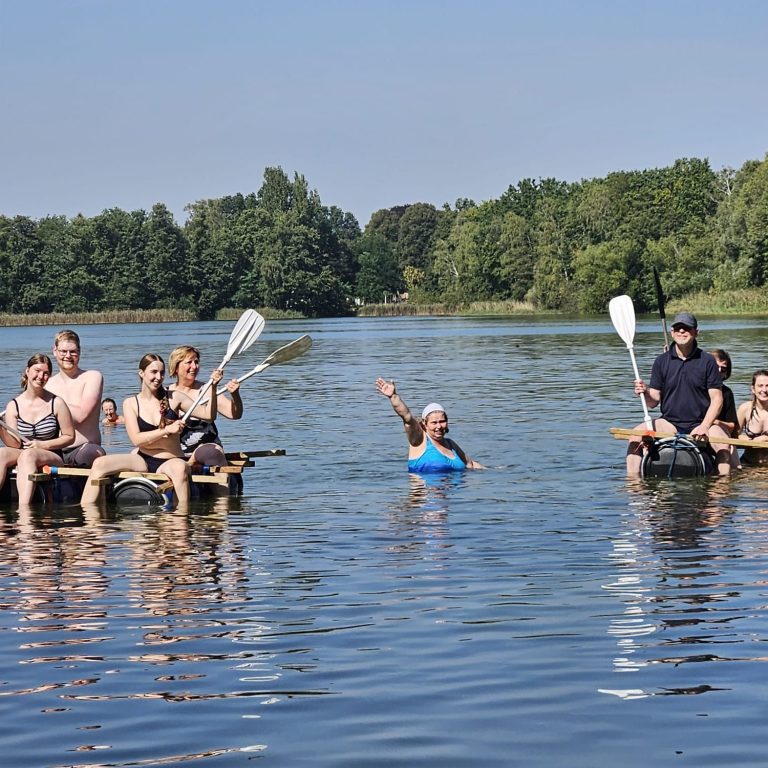 Gruppe von Paddlern auf dem Wasser, eine Person hebt die Hand.