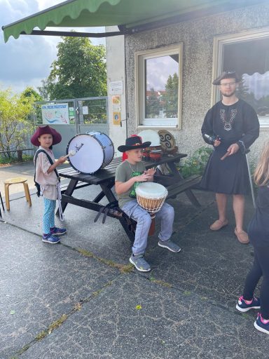 Kinder spielen Musik mit verschiedenen Instrumenten im Freien.