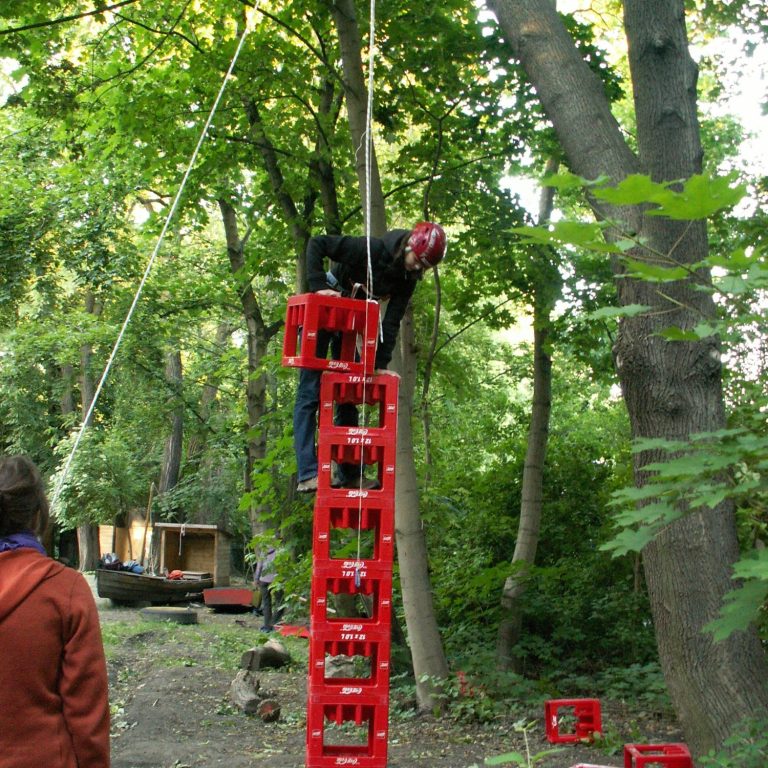 Person steht auf einem gestapelten Kisten Turm in einem Waldgebiet.