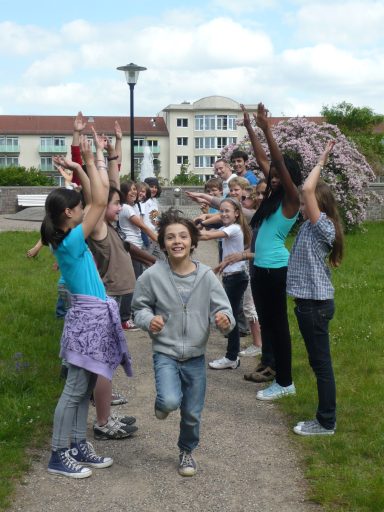 Eine Gruppe von Kindern jubelt, während ein Junge fröhlich auf dem Weg läuft.