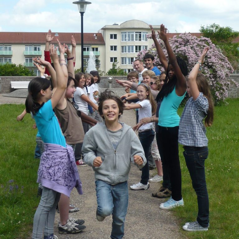 Gruppe von Kindern und Jugendlichen, die im Freien feiern und Freude zeigen.