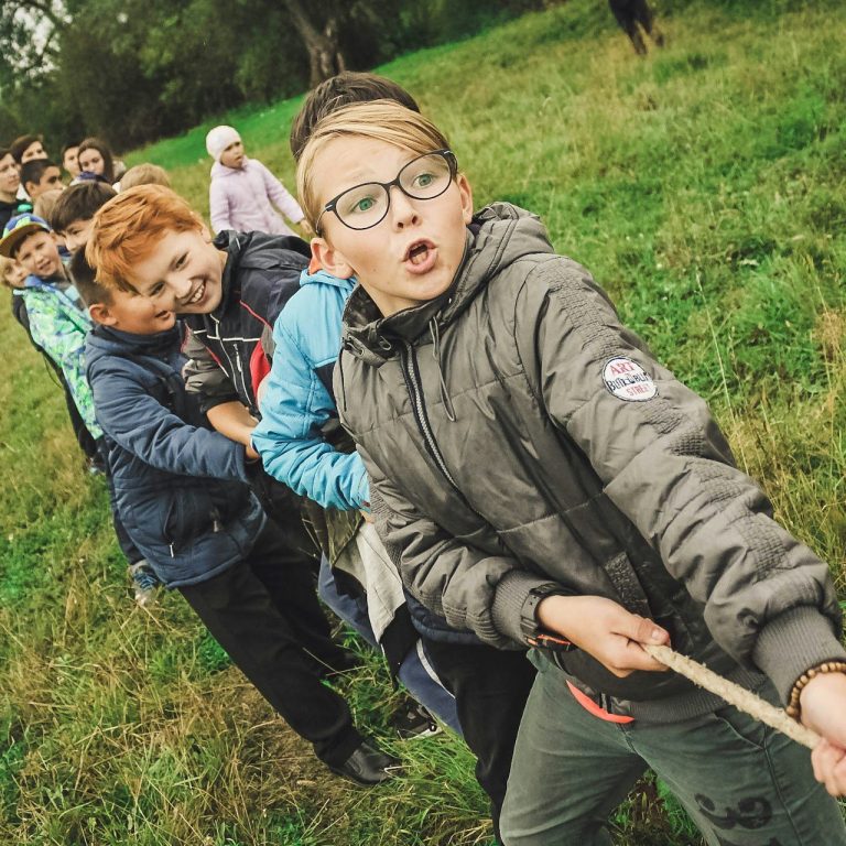 Kinder ziehen in einer Gruppenaktivität an einem Seil im Freien.